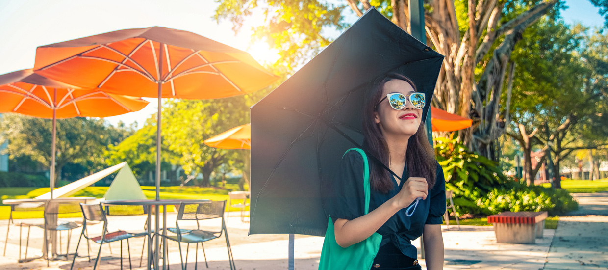 Student with umbrella in sun